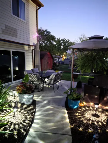 a view of a patio with table and chairs potted plants and large tree