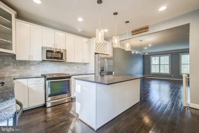 a kitchen with stainless steel appliances granite countertop a sink stove and wooden floor