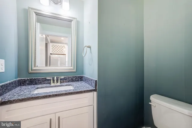 a bathroom with a granite countertop toilet a sink and mirror
