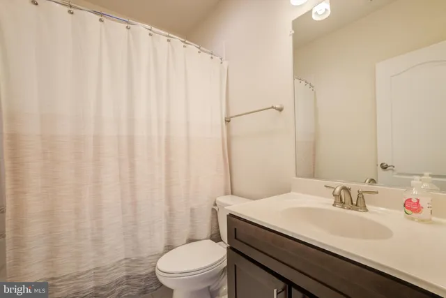a bathroom with a granite countertop sink and a toilet