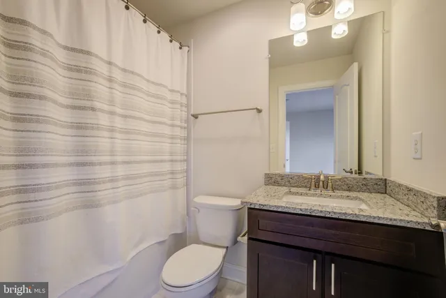 a bathroom with a granite countertop toilet sink and mirror