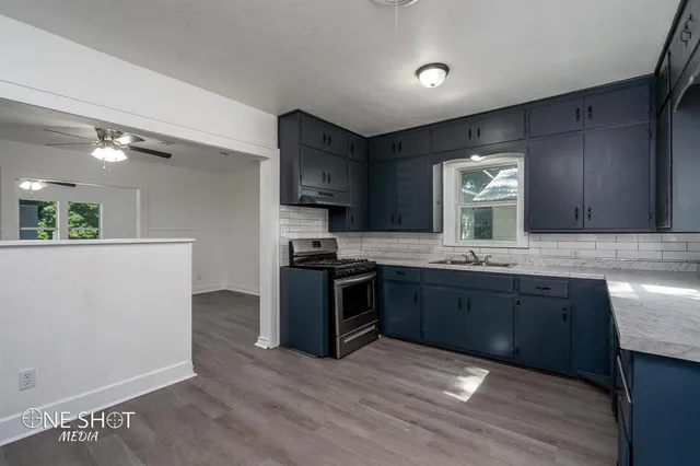 a kitchen with granite countertop a sink cabinets and stainless steel appliances