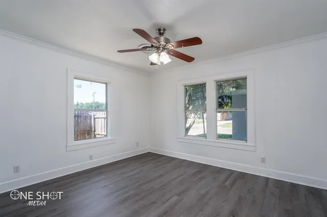a view of empty room with wooden floor and fan