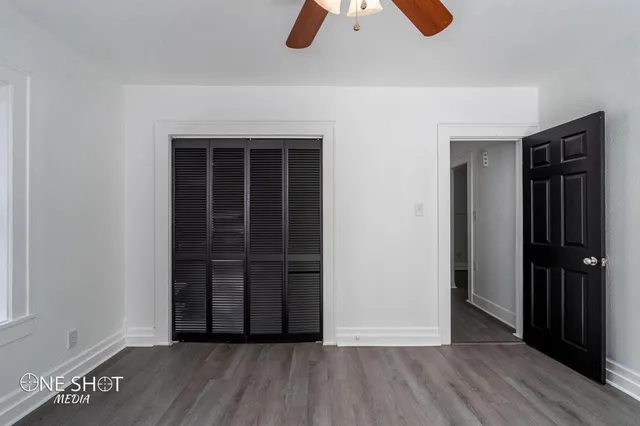 an empty room with wooden floor closet and windows