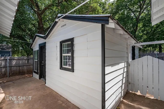 a view of house with wooden fence and large trees