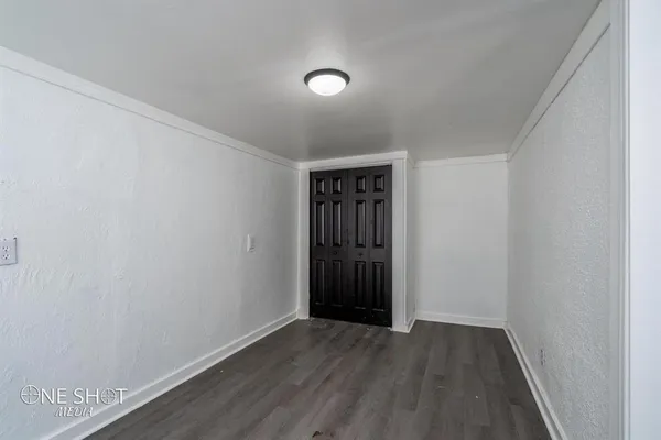 a view of an empty room with wooden floor and closet