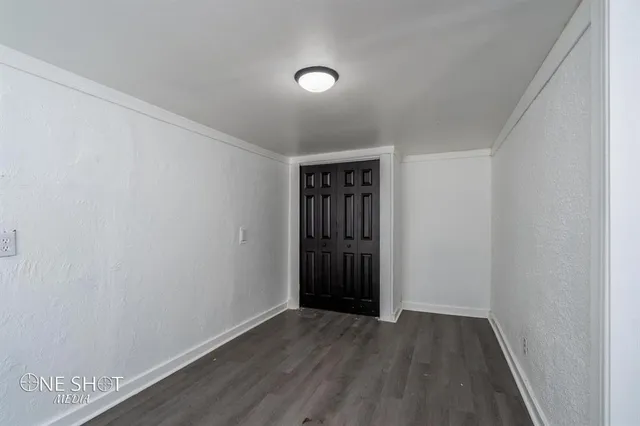 a view of an empty room with wooden floor and closet