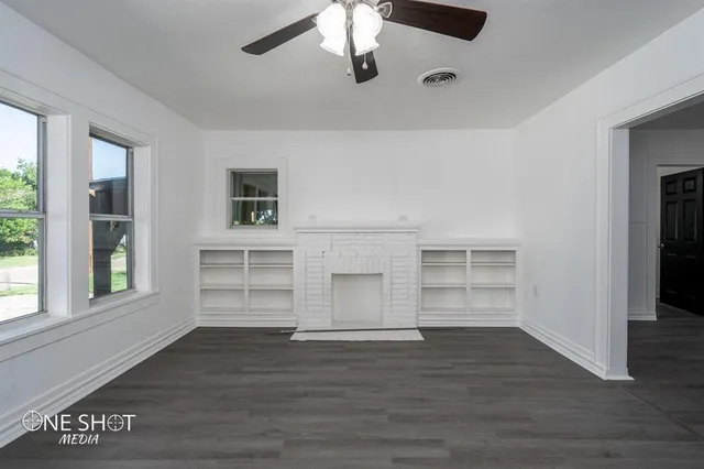 a view of an empty room with a window and wooden floor