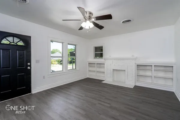 a view of an empty room with a window and wooden floor