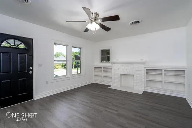a view of an empty room with a window and wooden floor