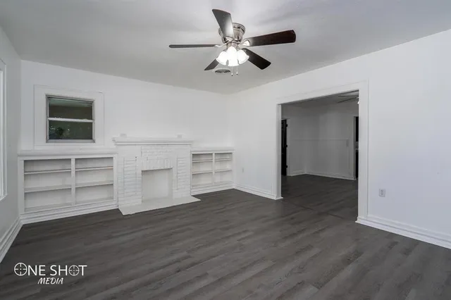 a view of an empty room with a window and wooden floor