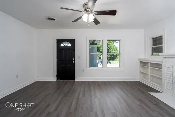 a view of an empty room with a window and wooden floor