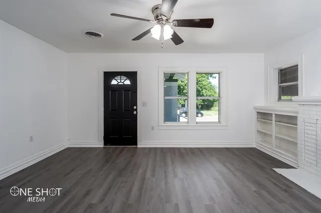 a view of an empty room with a window and wooden floor
