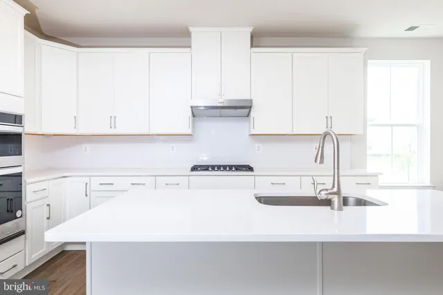 a kitchen with a sink a stove and white cabinets