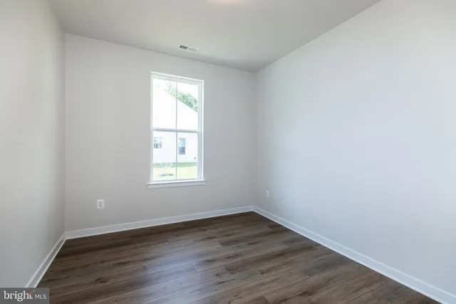an empty room with wooden floor and window