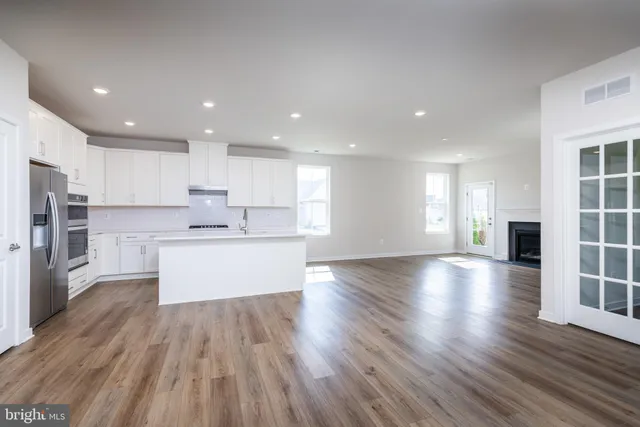 a large kitchen with stainless steel appliances sink large window and wooden floor