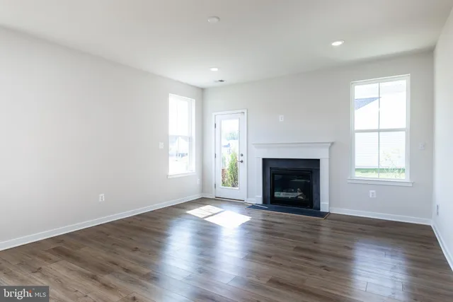 an empty room with wooden floor fireplace and windows