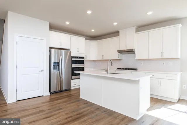 a kitchen with stainless steel appliances granite countertop a refrigerator sink and white cabinets