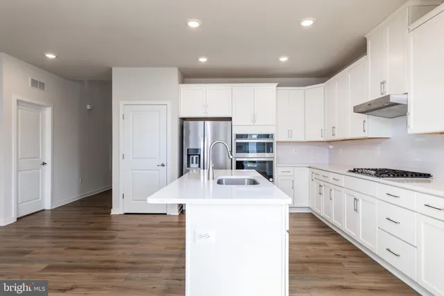 a kitchen with stainless steel appliances kitchen island sink refrigerator and cabinets