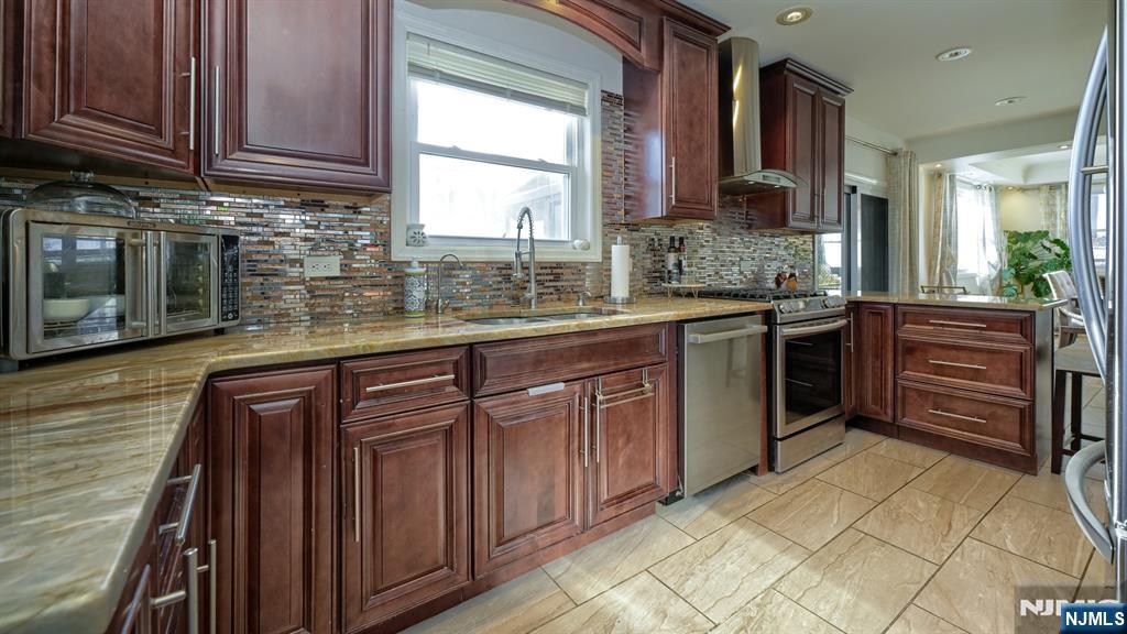 224 Pompton Road Haledon, NJ 07508 - Photo 11 of 34 a kitchen with stainless steel appliances granite countertop wooden cabinets a stove top oven with a sink and dishwasher