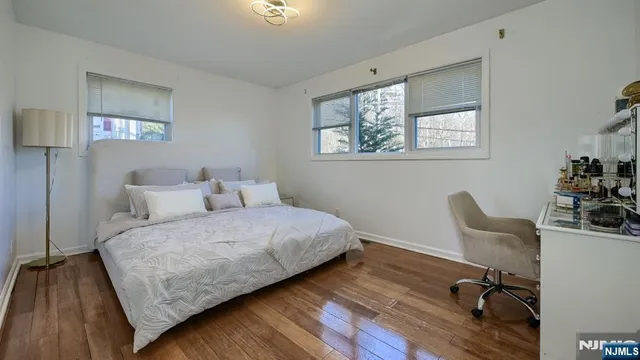a bedroom with a bed chair and wooden floor