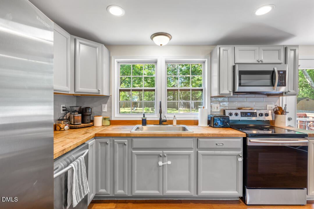 454 Cedar Creek Road Timberlake, NC 27583 - Photo 17 of 39 a kitchen with stainless steel appliances granite countertop a sink a stove a microwave a refrigerator and cabinets