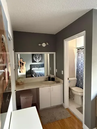 a room with a sink a large mirror and a toilet