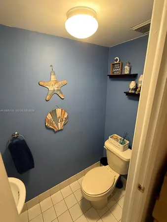 a white toilet sitting next to a bathroom sink and a mirror