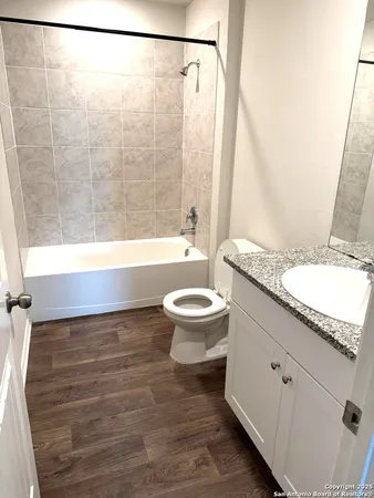 a bathroom with a granite countertop bathtub shower sink vanity and toilet