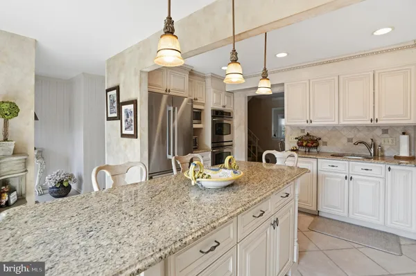 a kitchen with kitchen island granite countertop a sink cabinets and living room view