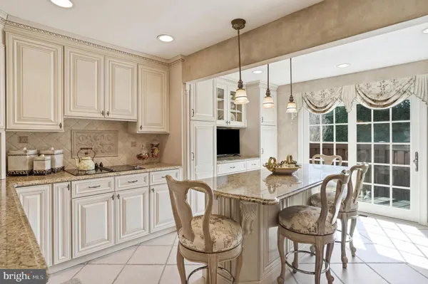 a kitchen with granite countertop a table chairs stove and white cabinets