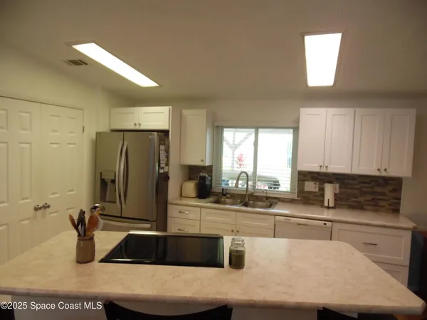 a kitchen with kitchen island granite countertop a sink a counter top space cabinets and stainless steel appliances