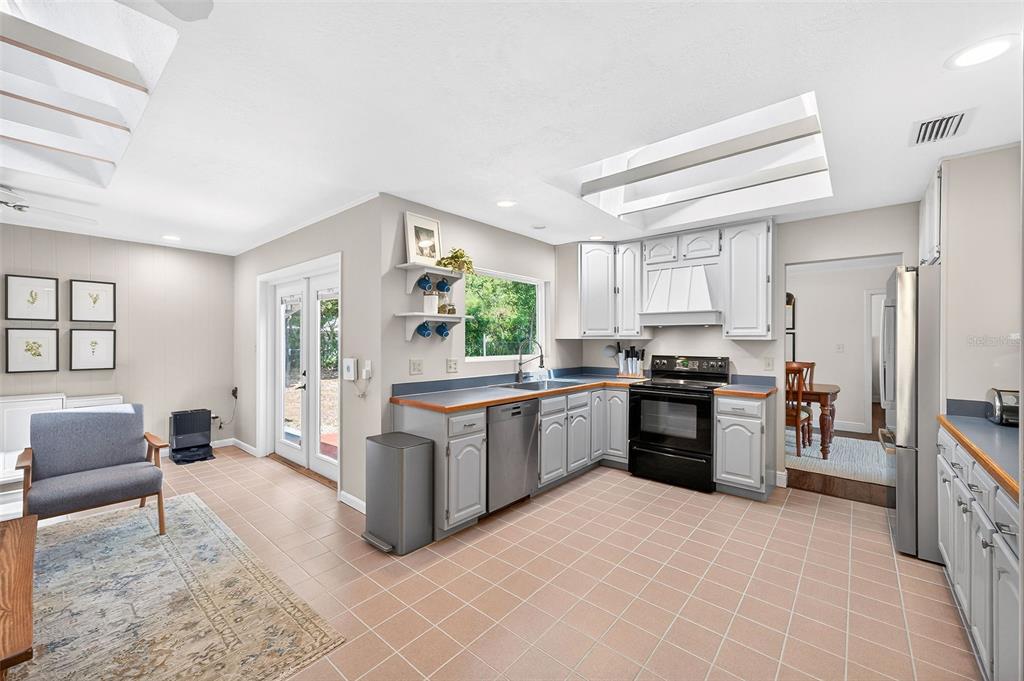 517 Roughbeard Road Winter Park, FL 32792 - Photo 48 of 53 a kitchen with stainless steel appliances granite countertop a stove top oven a sink dishwasher a dining table and chairs with wooden floor