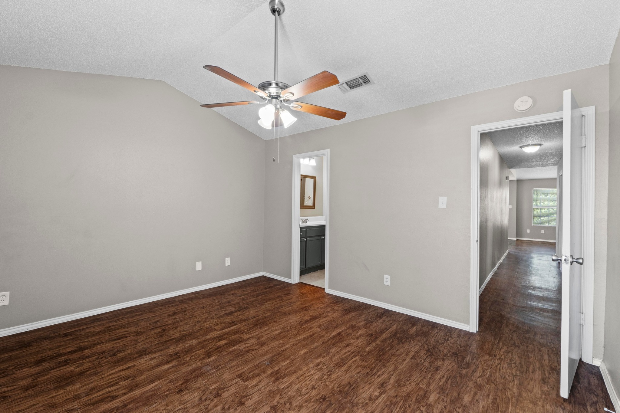 4208 Duval Road, Unit C Austin, TX 78759 - Photo 14 of 28 Unfurnished bedroom featuring dark wood-style floors, vaulted ceiling, a textured ceiling, ceiling fan, and ensuite bathroom