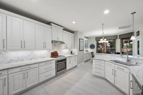 a kitchen with kitchen island granite countertop white cabinets white stainless steel appliances with a sink and dishwasher
