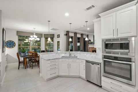 a kitchen with stainless steel appliances kitchen island granite countertop a stove and white cabinets