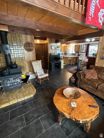 1456 Navajo Road Coalville, UT 84017 - Photo 10 of 55 Living area with wood walls, a wood stove, and a wood ceiling with exposed beams
