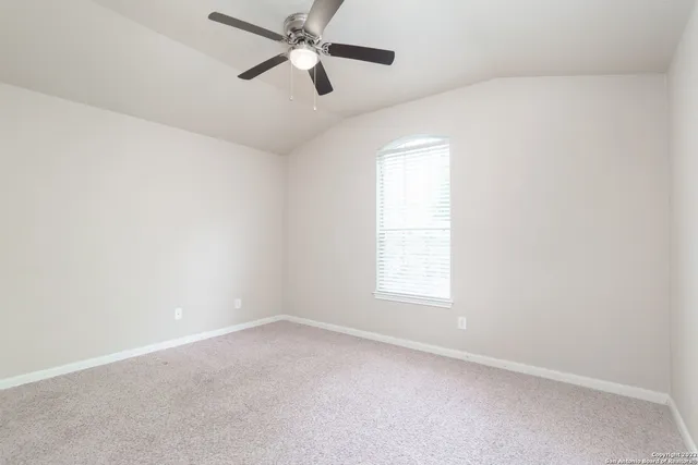 an empty room with a window and a fan
