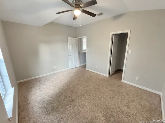 an empty room with a ceiling fan and a window