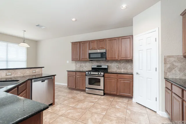 a kitchen with stainless steel appliances granite countertop a stove top oven a sink dishwasher and a refrigerator