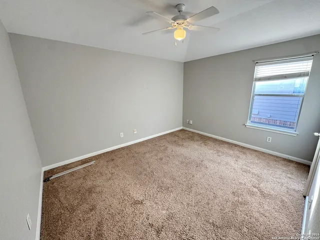 an empty room with a window and a ceiling fan