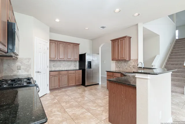 a kitchen with stainless steel appliances granite countertop a stove a sink and a refrigerator
