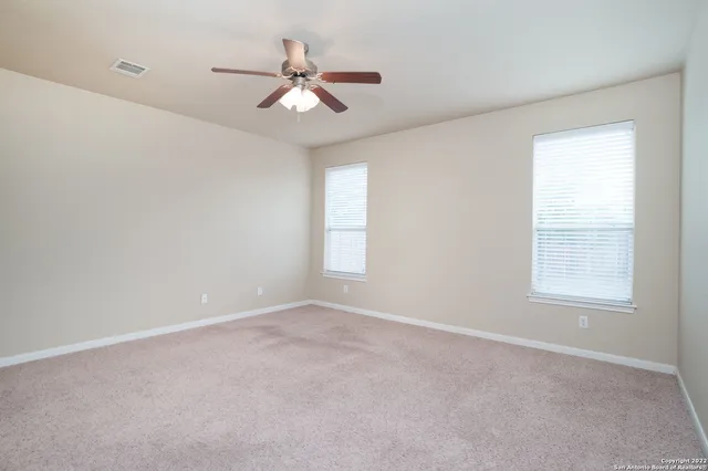 an empty room with windows and fan