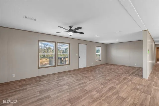 a view of an empty room with a window and wooden floor