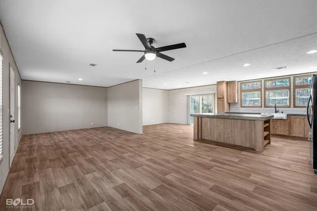 a view of kitchen and empty room with wooden floor
