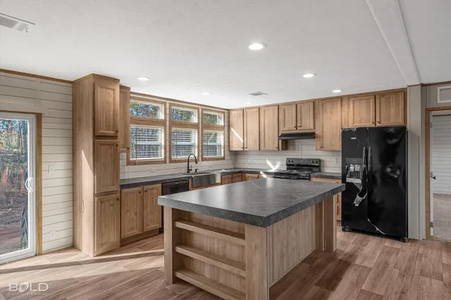 a kitchen with kitchen island granite countertop a sink stove and refrigerator