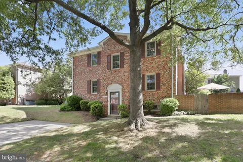 a view of a brick house with a yard and large tree