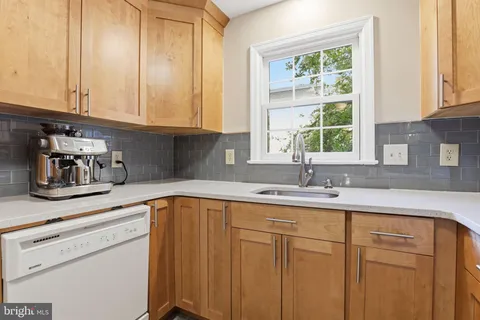 a kitchen with stainless steel appliances granite countertop white cabinets sink and window