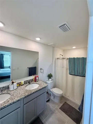 a bathroom with a granite countertop sink a mirror a toilet and a shower