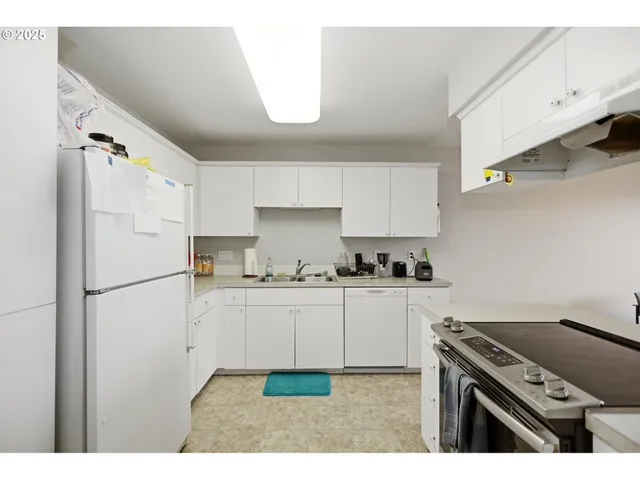 a kitchen with stainless steel appliances granite countertop a refrigerator a stove a sink and white cabinets